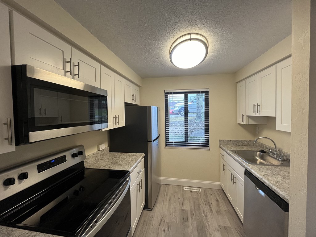 a kitchen with stainless steel appliances and white cabinets a kitchen with stainless steel appliances and white cabinets at Deauville Park Apartments, Monroeville, PA