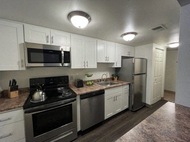 A kitchen with white cabinets and stainless steel appliances.