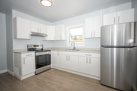 A kitchen with white cabinets and a stainless steel refrigerator.