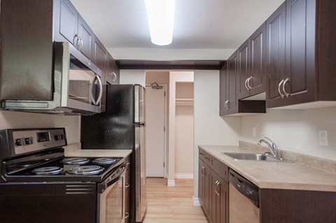 a kitchen with dark wood cabinets and stainless steel appliances