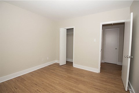 a bedroom with wood flooring and a door to a closet