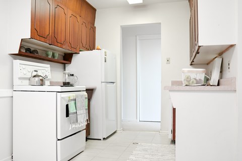A white fridge and oven in a kitchen with wooden cabinets.