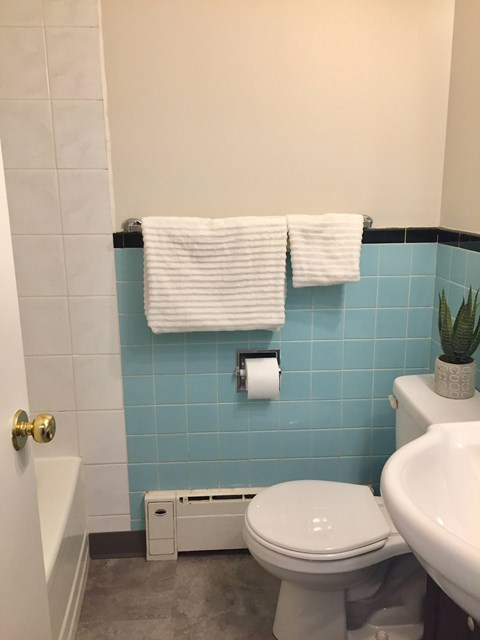 Clean bathroom with light blue tile, white towels, and modern fixtures at 359 Edison Apartments.