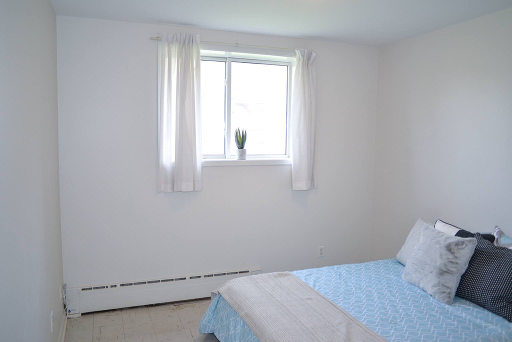 A bedroom with a bed and a window with curtains.