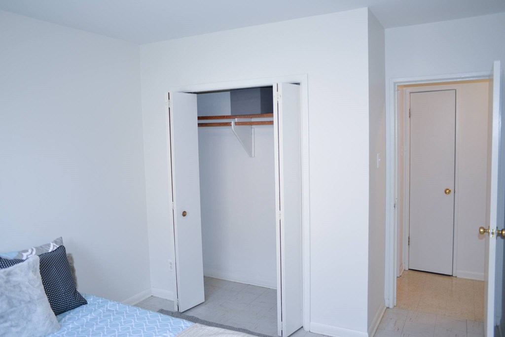 A white bedroom with a bed and a closet.