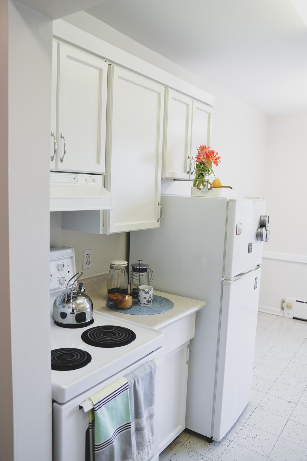A white kitchen with a stove and refrigerator.