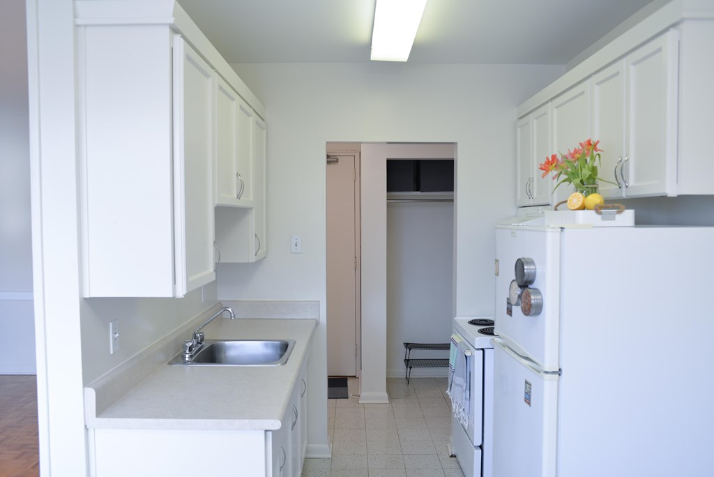 A kitchen with white cabinets and a white fridge.