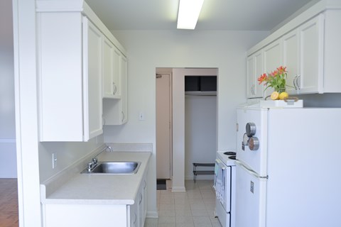 A kitchen with white cabinets and a white fridge.