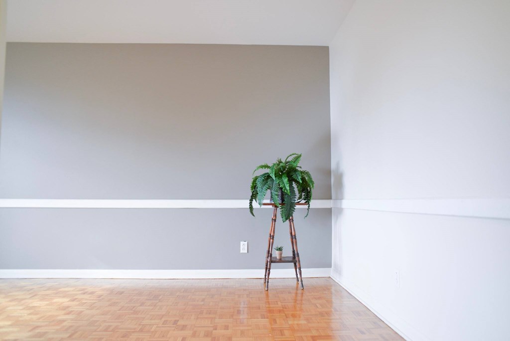 A potted plant sits on a stand in a room with white walls.