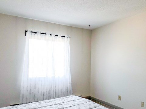 A bedroom with a bed and a window with curtains.