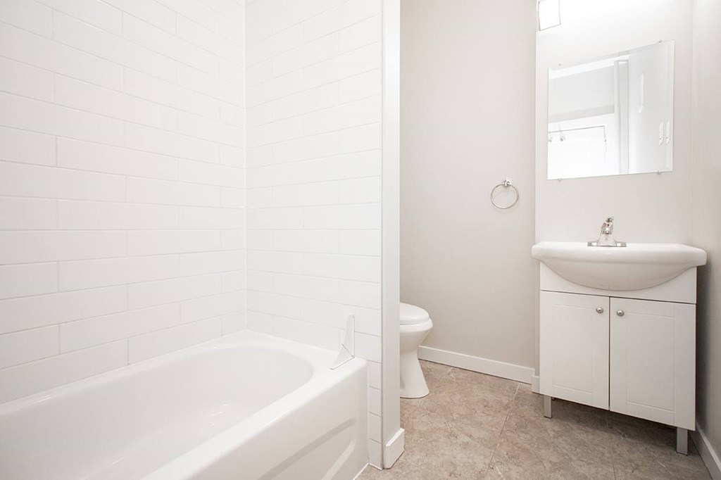 A white bathroom with a tub, toilet and sink.
