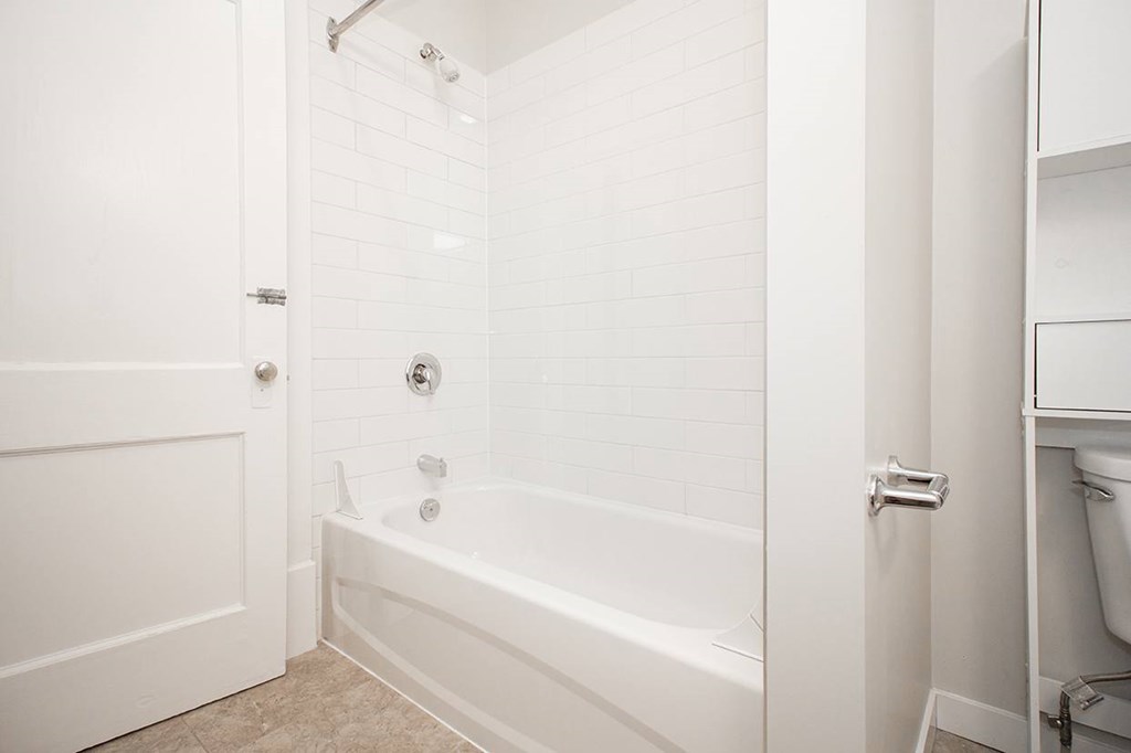 A white bathroom with a tub and toilet.