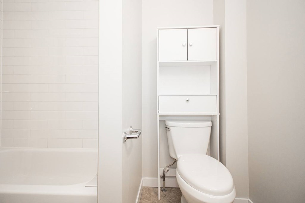A white toilet sits next to a white bathtub in a bathroom.