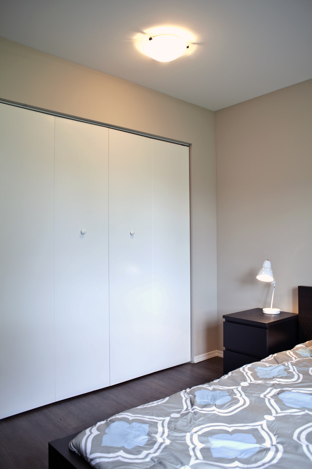 A bedroom with a bed, nightstand, and wardrobe.