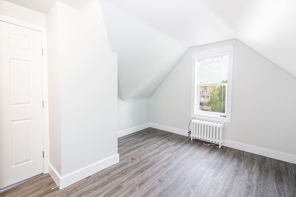 a bedroom with hardwood floors and a white door