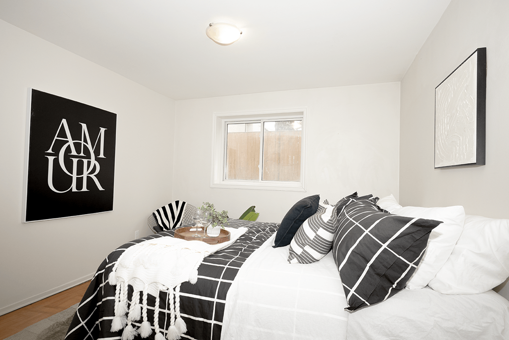A bedroom with a bed, pillows, and a poster on the wall.