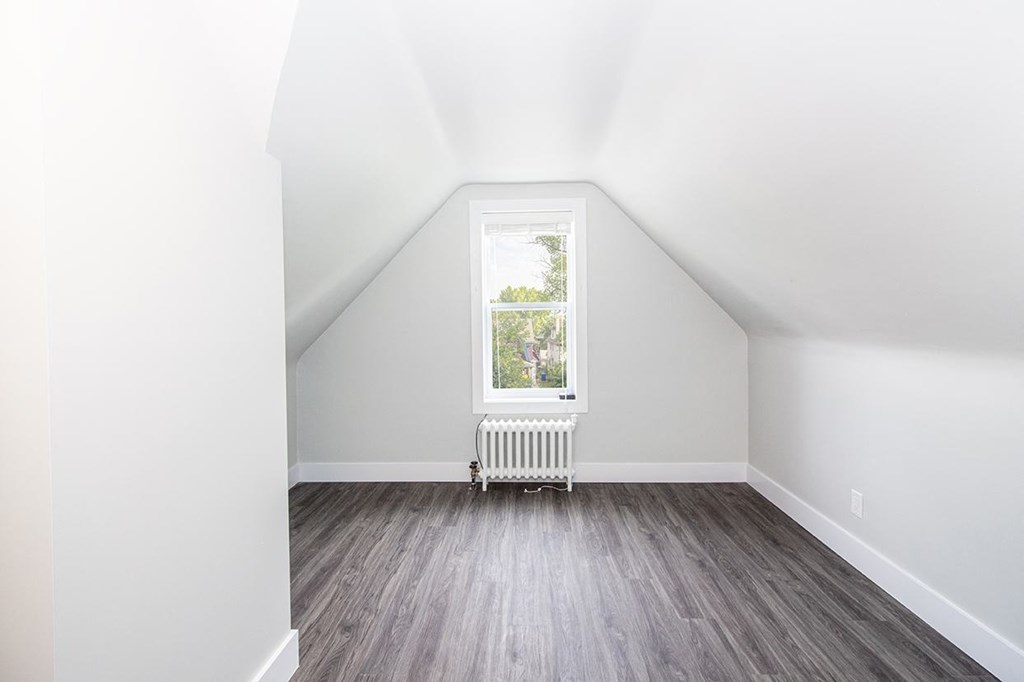 a small attic room with a window and a radiator