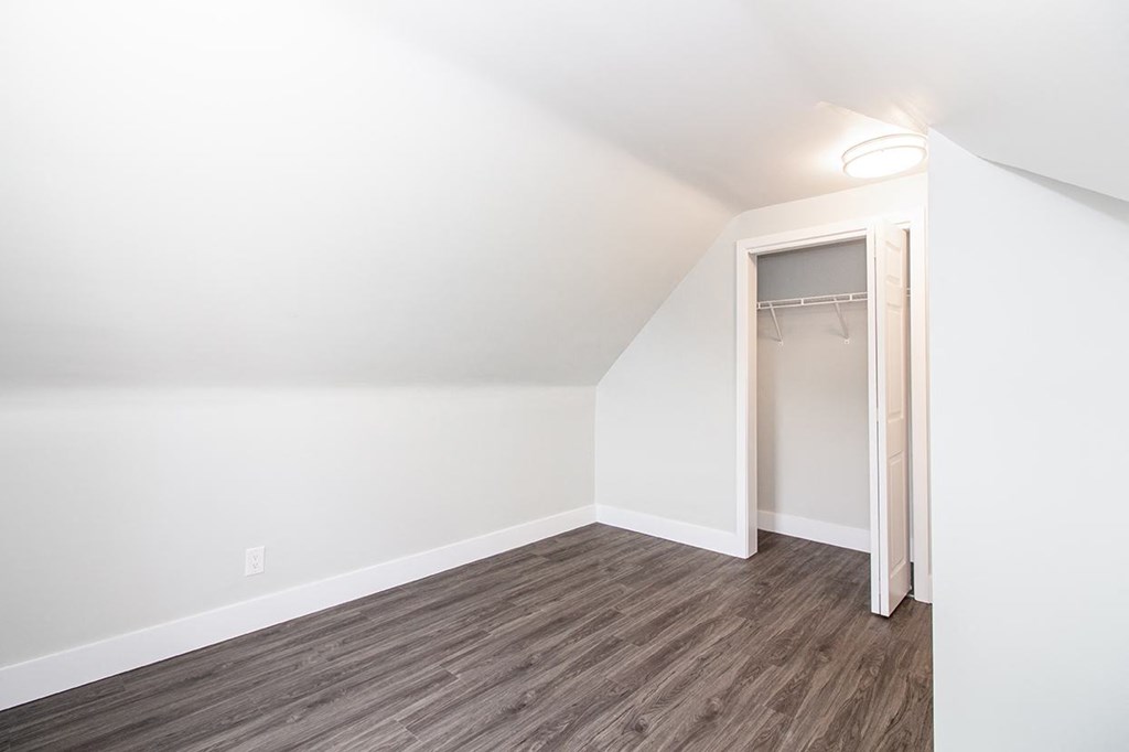 a bedroom with hardwood floors and white walls