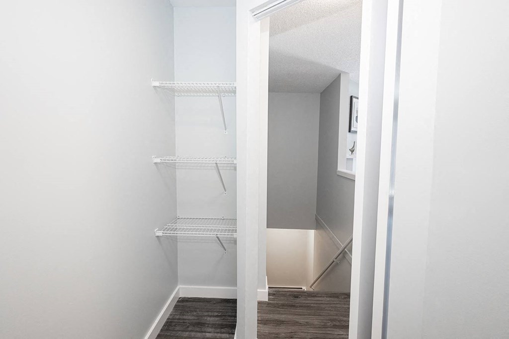 a closet in a small room with white walls and a wood floor