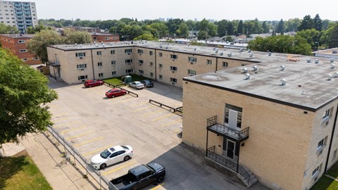 A parking lot with cars and a building with a balcony.