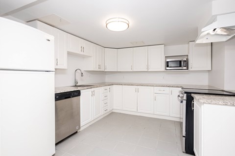 A white kitchen with a refrigerator on the left and a microwave on the right.