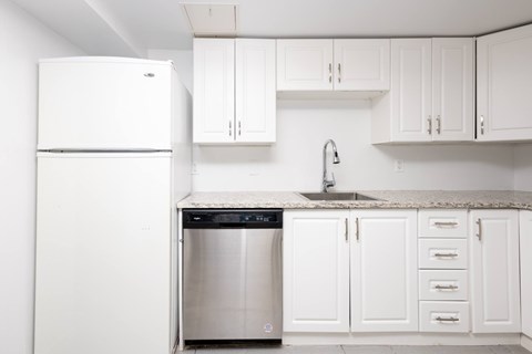 A white kitchen with a dishwasher and fridge.