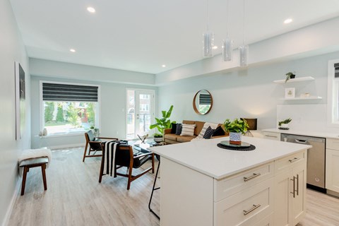 an open kitchen and living room with a white counter top