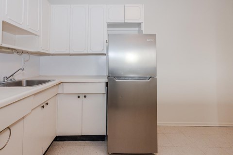 A kitchen with white cabinets and a stainless steel refrigerator.