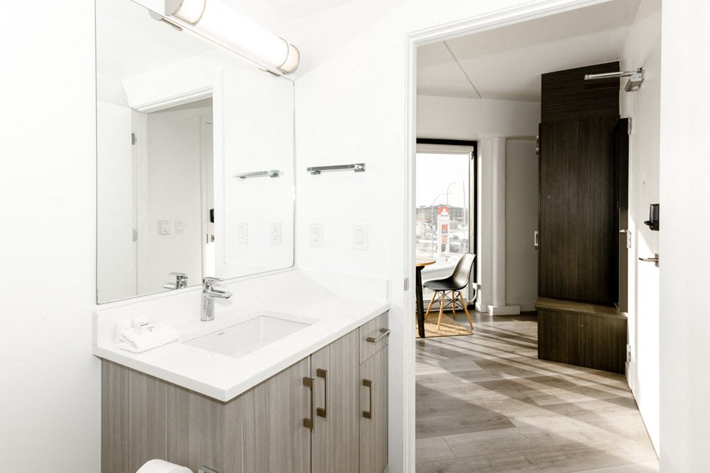 A bathroom with a sink, mirror, and a wooden cabinet.