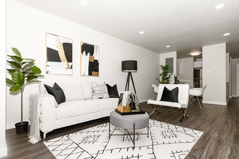 A living room with a white couch, a grey coffee table, and a black and white rug.