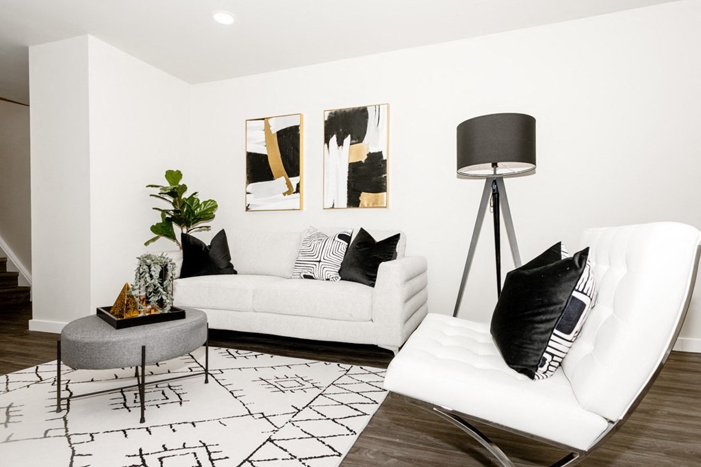 A white couch with black pillows sits in a room with a black and white rug.