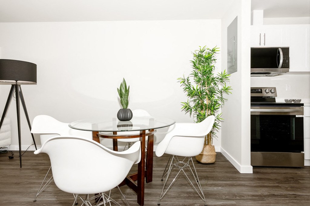 A white dining table with two chairs and a potted plant.