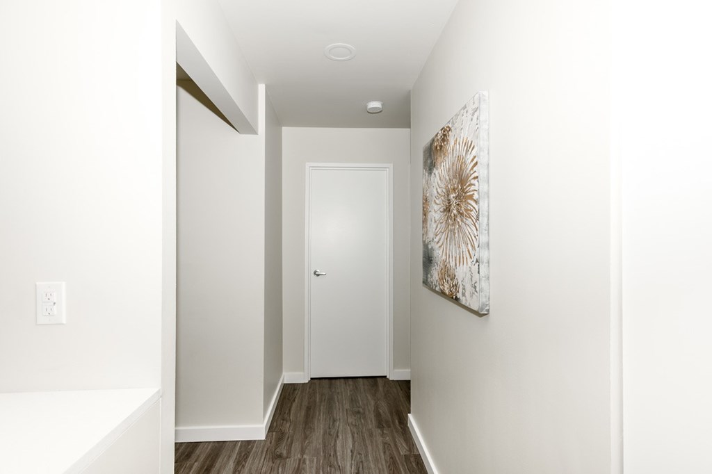 A hallway with a white door and a painting on the wall.