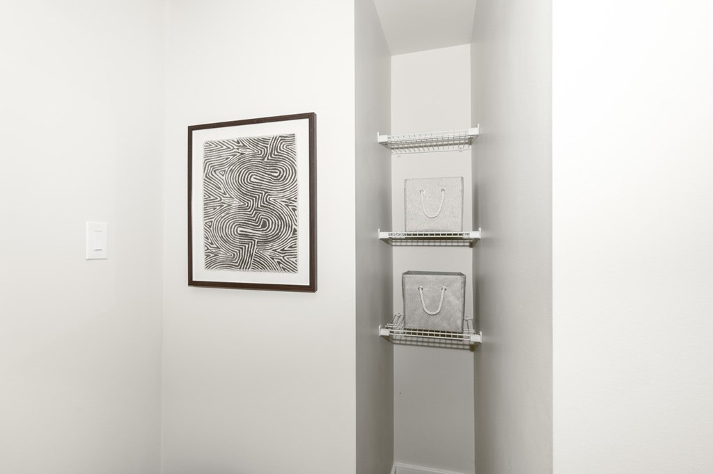 A picture is hanging on the wall next to a shelf with three boxes on it.