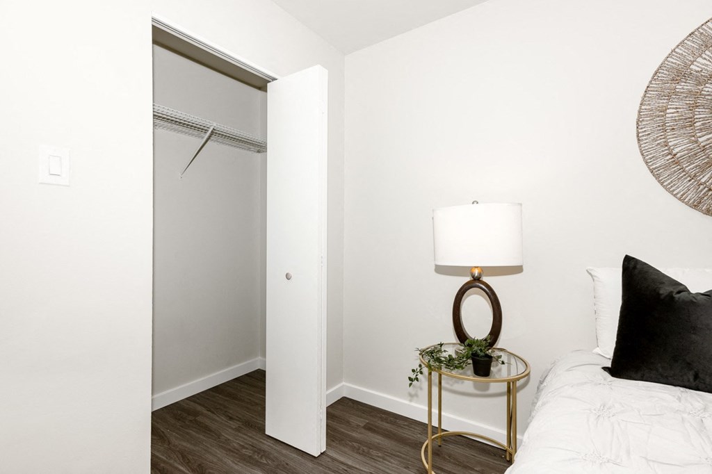 A bedroom with a bed, a lamp, and a plant.