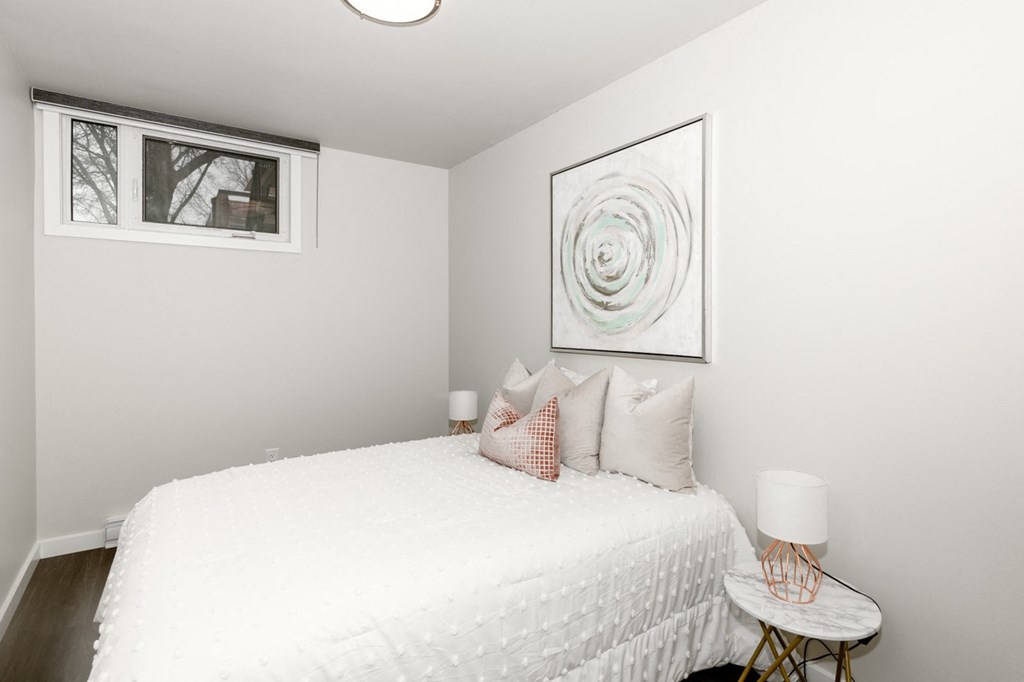 A bedroom with a white bed and a round painting on the wall.