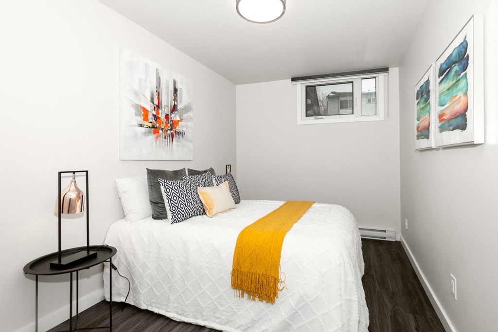 A bedroom with a white bed and a yellow throw.