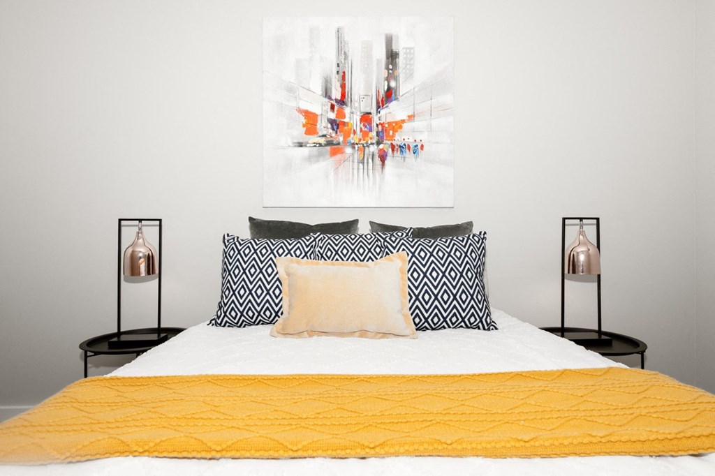 A bed with a yellow comforter and two pillows with a black and white pattern.