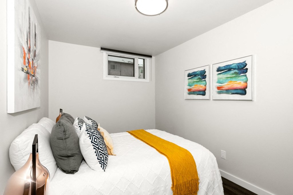 A bedroom with a bed, pillows, and artwork on the wall.