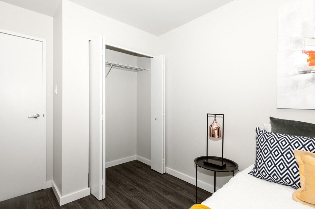 A white bedroom with a bed, nightstand, and a chair.