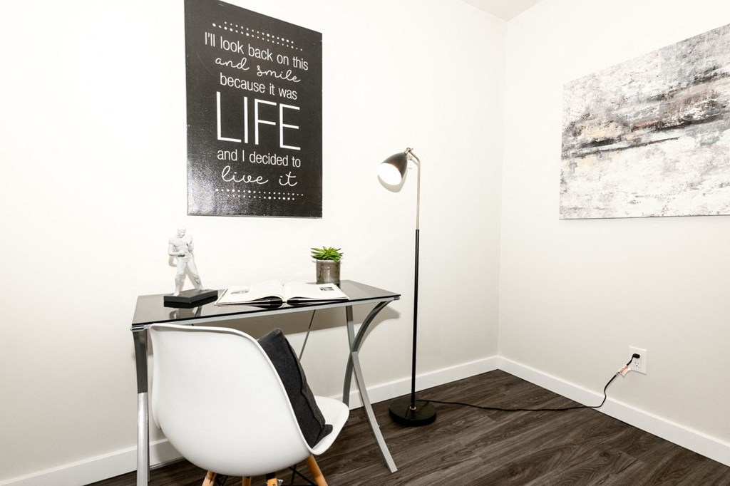 A poster with the word "LIFE" on it is hanging on a wall above a desk with a chair and a lamp.