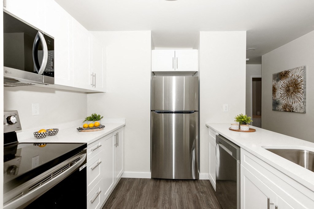 A modern kitchen with a stainless steel refrigerator and white cabinets.