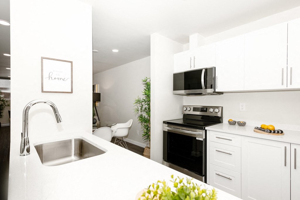 A modern kitchen with white cabinets and a stainless steel sink.