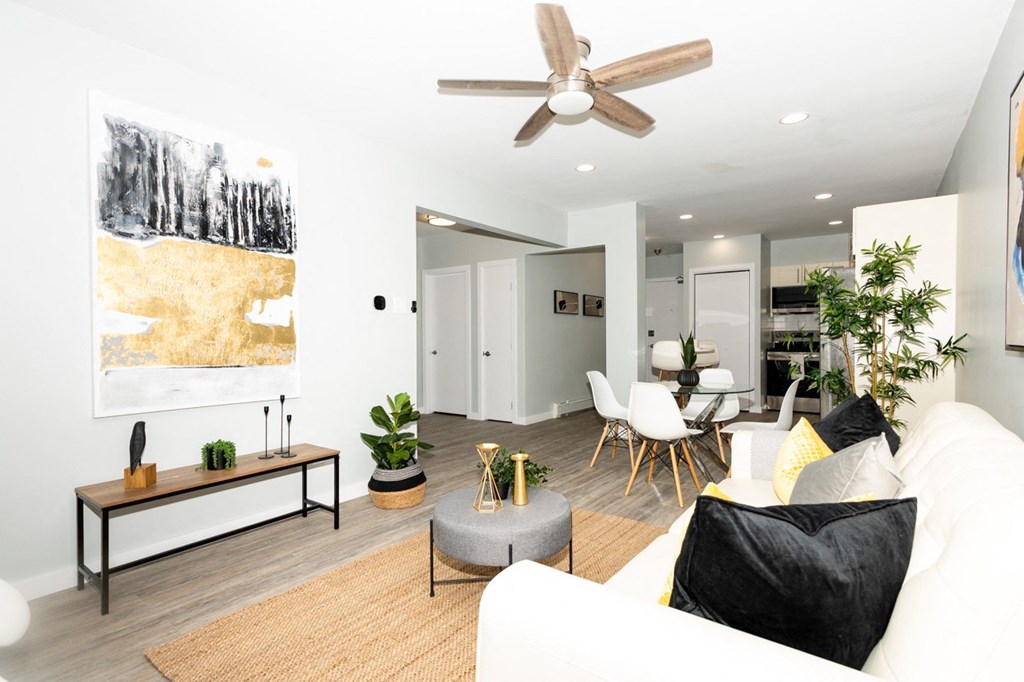 A living room with a white couch, a rug, a coffee table, and a painting on the wall.