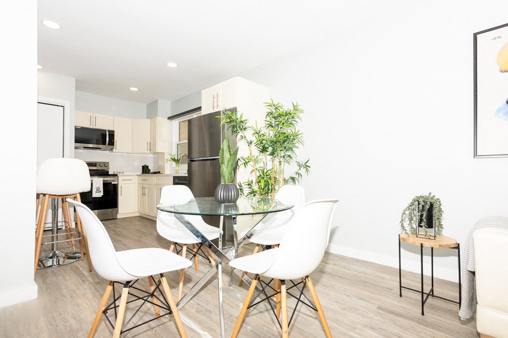 A modern kitchen with a glass table and white chairs.