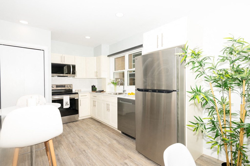 A modern kitchen with a refrigerator, oven, and a dining table.