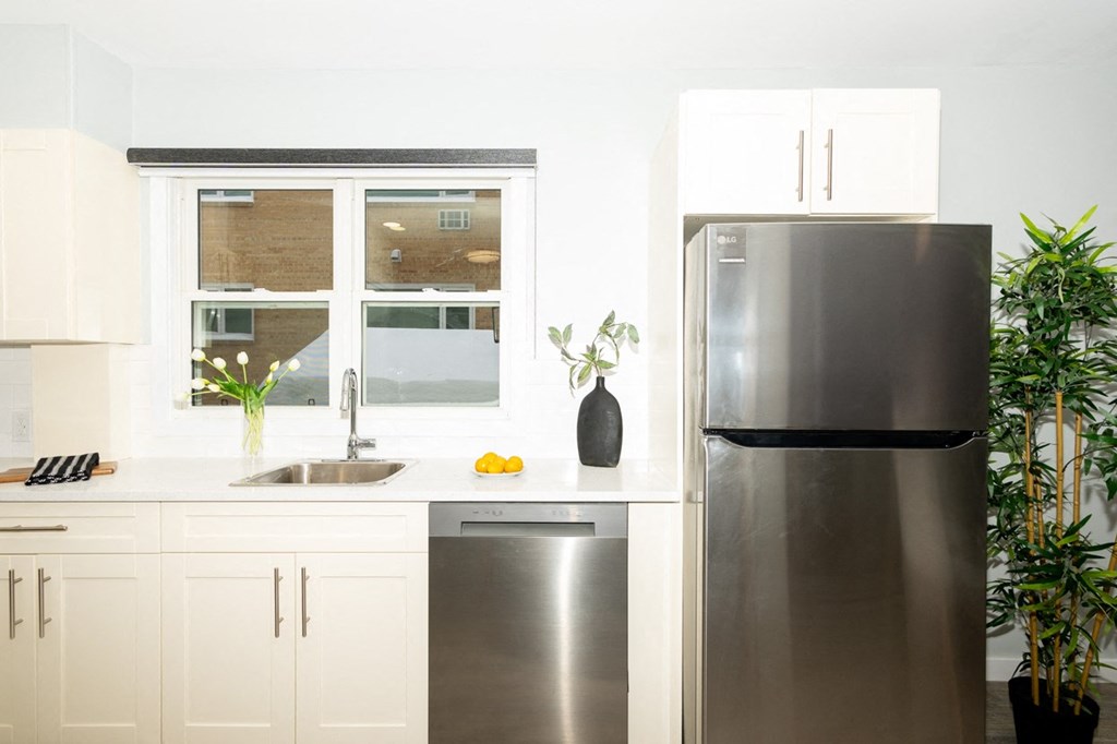 A modern kitchen with a stainless steel refrigerator and white cabinets.
