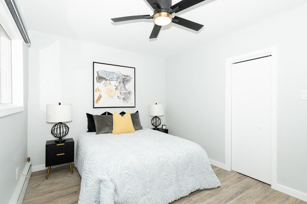 A bedroom with a bed, two lamps, and a ceiling fan.