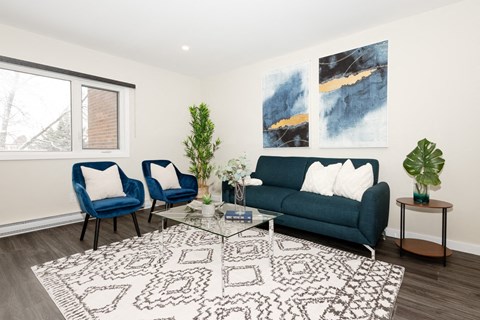 A living room with a blue couch, two chairs, and a patterned rug.
