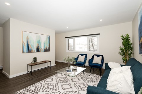 A living room with a blue couch and a painting on the wall.